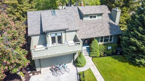 A two-story house with a garage, a covered patio, and a well-maintained lawn. - Green Gables-2 Fireplaces,Salt Hot tub, 100+mbps Wifi, AC, Bikes, Big Yard,Walk! (Bend)