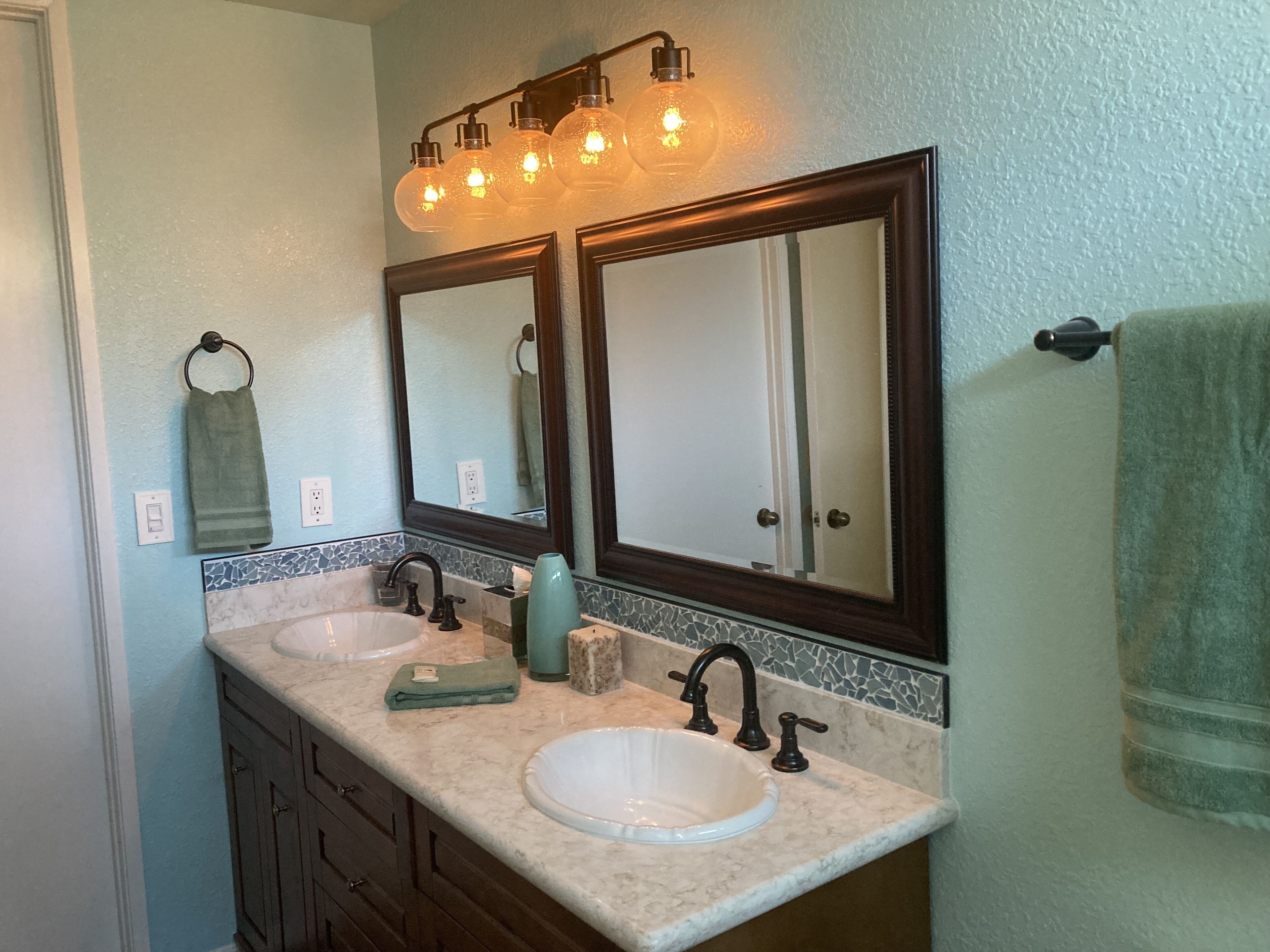 A bathroom with two sinks, a mirror, and a towel rack.