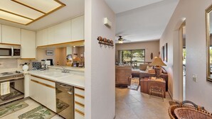 A modern kitchen with stainless steel appliances, a large island, and a dining area with a sofa and table. - Desert Princess Cc And Resort, On Golf Course, W/ Mountain Views (Cathedral City)