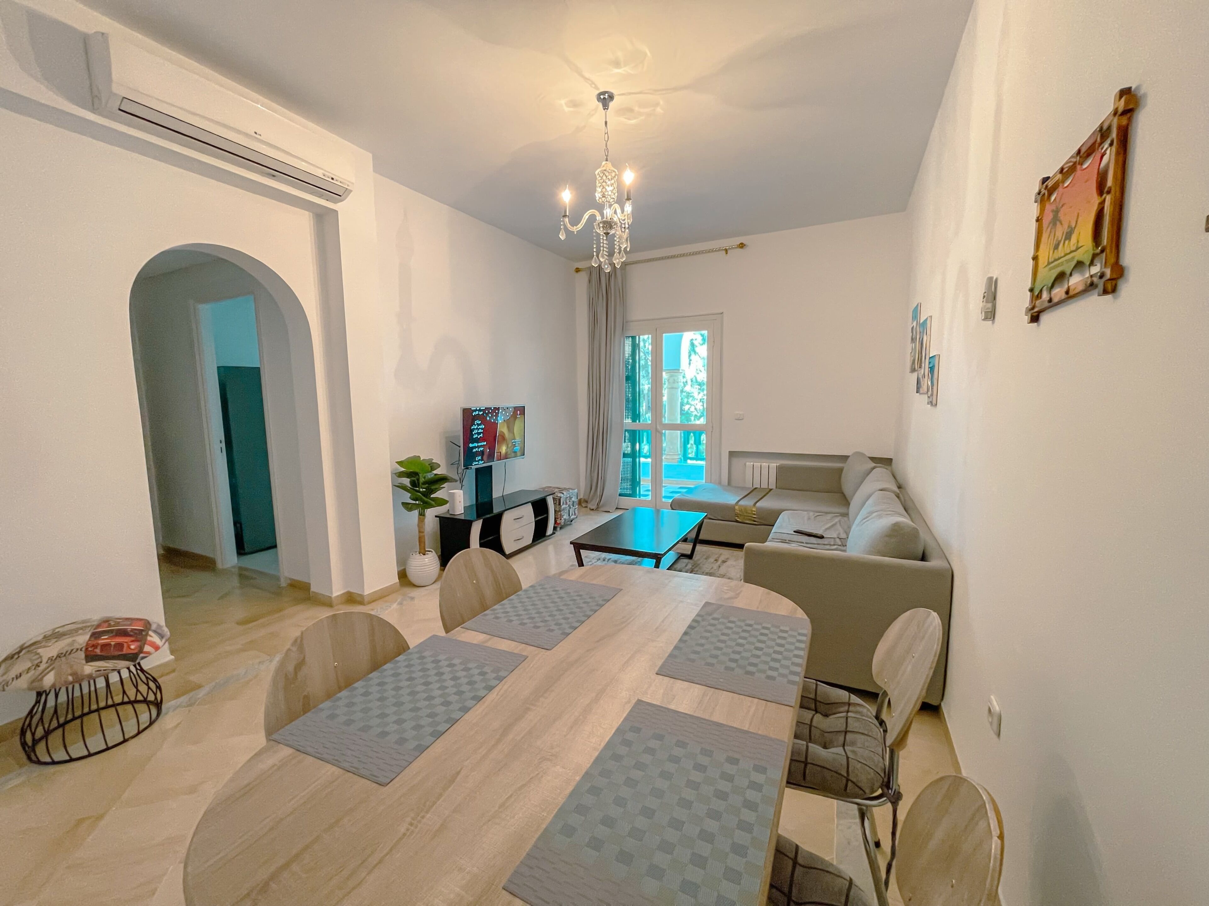 Una sala de estar moderna con comedor, una araña y un televisor.