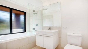 Un baño moderno con cabina de ducha de vidrio, un lavabo blanco y un inodoro.