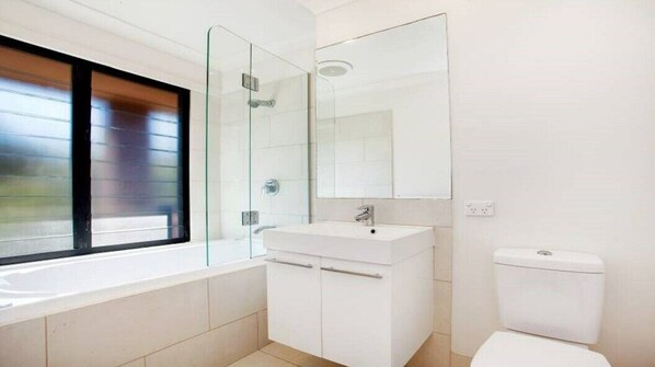 A modern bathroom with a glass shower enclosure, a white sink, and a toilet.