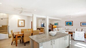 Una cocina moderna con encimera de granito, mesa de comedor de madera y sillas de mimbre.