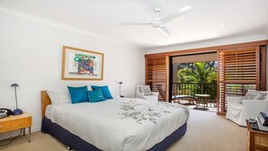 Un dormitorio con una cama grande, un ventilador de techo, un cuadro enmarcado en la pared y un balc ón con muebles de exterior.