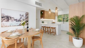 A modern kitchen with white cabinets, wooden stools, and a large island.