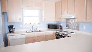 A modern kitchen with light wooden cabinets, a stainless steel sink, a microwave, and a stove. - Perfect Gulf Front Beach House *Beach Club Amenities*The Best of Both Worlds! (Gulf Shores)