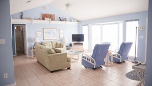 A spacious living room with a beige sofa, two blue armchairs, a television, and a ceiling fan. - Perfect Gulf Front Beach House *Beach Club Amenities*The Best of Both Worlds! (Gulf Shores)