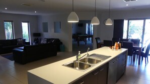 A modern kitchen with a central island, stainless steel sink, and pendant lighting. - Parkins Fairway - Golf, Lake & Relaxation (Yarrawonga)