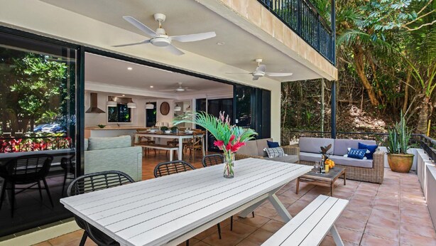 Eine Terrasse im Freien mit Esstisch, Stühlen und Deckenventilator.