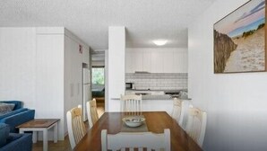 A compact living space with a dining area, kitchenette, and a view of the outdoors. - 2/56 Lawson Street at Clarkes Beach (Byron Shire)