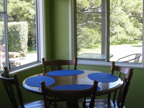 Enjoy meals in this dining area with a round table and six chairs, surrounded by a lush garden view.
