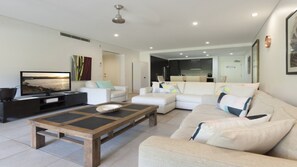 Relax in this stylish living room with a flat-screen TV, coffee table, and comfortable sofas.