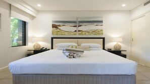 Contemporary hotel room with a large bed, abstract art, and minimalist decor.