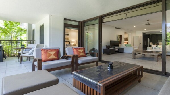 Relax in a spacious living area with sofas, a coffee table, and sliding glass doors leading to a balcony with outdoor furniture.