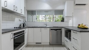 Enjoy cooking in this kitchen with sleek cabinetry, a dishwasher, and a countertop, offering a view of the surrounding greenery.