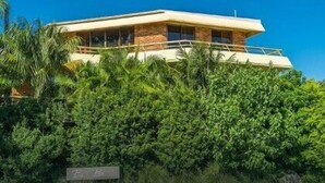 A modern building with a flat roof, large windows, and a sign indicating a parking area. - Breeze at Byron 1 Clarkes Beach (Byron Shire)
