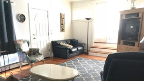 Ein Wohnzimmer mit einer Couch, einem gemusterten Teppich, einem kleinen Tisch und einem Fernseher.