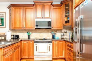 A kitchen with wooden cabinets, a stainless steel refrigerator, a microwave, and a stove. - Beach Therapy - Oceanfront!! 4 BR / 3 BA Enjoy the views from Master Bedroom! (Topsail Beach)