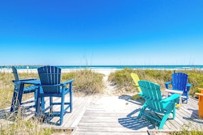 A wooden boardwalk leading to a beach with several colorful Adirondack chairs. - Beach Therapy - Oceanfront!! 4 BR / 3 BA Enjoy the views from Master Bedroom! (Topsail Beach)
