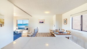 A modern dining area with a large marble table, wooden chairs, and a view of the sea through large windows. - Intrepid, 15 3 Intrepid Close - right on the beachfront and WiFi (Nelson Bay)