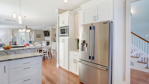 A modern kitchen with white cabinetry, stainless steel appliances, and a marble countertop. - Heated Pool Access | 5*Clean | Flex Cancelation (Tybee Island)