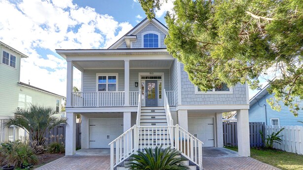 A two-story house with a front porch, a central staircase, and a driveway. - Heated Pool Access | 5*Clean | Flex Cancelation (Tybee Island)