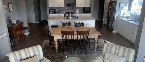 A modern kitchen with white cabinets, a central island, and a dining area with wooden chairs.