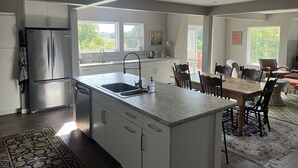 A modern kitchen with a central island, stainless steel appliances, and a dining area with a table and chairs.