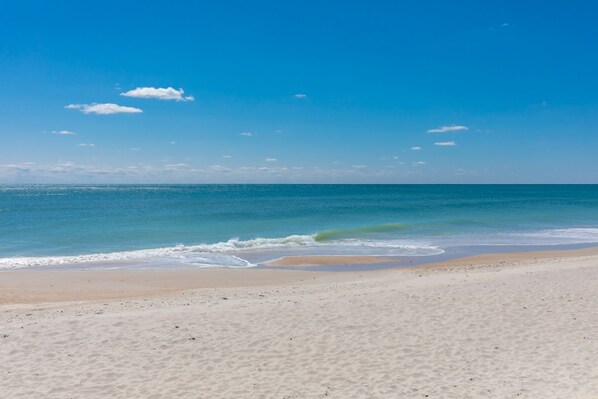 Ein Strand mit blauem Himmel und ruhigem Wasser.