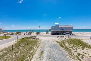 A beachfront property with a two-story building, a covered walkway, and a clear view of the ocean.