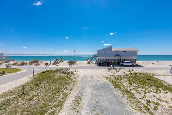 Une propriété située en bord de mer, comprenant un bâtiment à deux étages, une allée couverte et une vue dégagée sur l’océan.