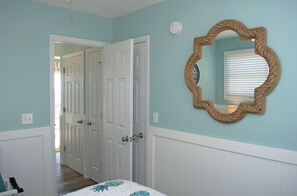 A bedroom with a bed, a door, and a wall-mounted mirror.