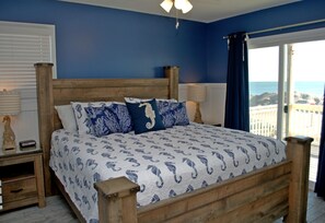 A bedroom with a wooden bed, a view of the sea, and a balcony.