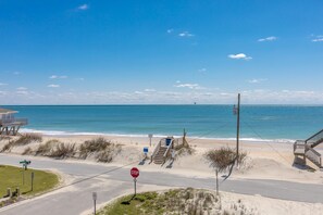 A beach view with a stop sign, a lifeguard tower, and a clear sky.