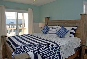 Une chambre à coucher avec un lit, une tête de lit en bois et une vue sur l’extérieur.