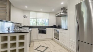 A modern kitchen with white cabinetry, stainless steel appliances, and a window providing natural light.