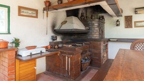 A rustic kitchen with a brick oven, wooden counter, and various kitchen utensils.