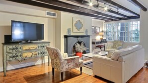 Uma sala de estar com televisão, lareira, sofá e poltrona.