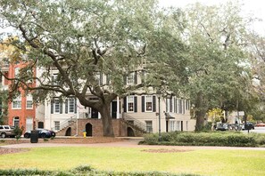 A historic building with a large tree in front, brick walls, and a small staircase leading to the entrance. - Heated Pool Access | 5*Clean | Flex Cancelation (Savannah)