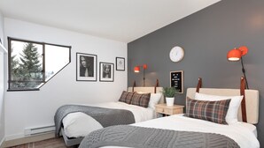 Una camera da letto moderna con due letti, un'ampia finestra e vista sugli alberi.