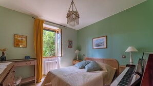 Una camera da letto con un letto, un pianoforte, una scrivania e una finestra con tende.