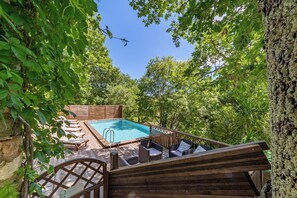 A pool area with a wooden deck, lounge chairs, and a hot tub. - Stone farmhouse with pool (Saint-André-de-Roquepertuis)
