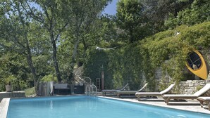 Una piscina con lettini e un muro in pietra.