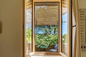 A room with a view of a garden through a glass door. - Stone farmhouse with pool (Saint-André-de-Roquepertuis)
