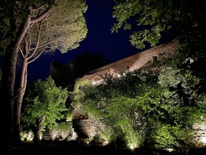 Un edificio de piedra con techo inclinado, rodeado de abundante follaje y árboles.
