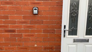 Paredes de tijolos vermelhos com uma porta branca, um painel de vidro e maçaneta de metal.