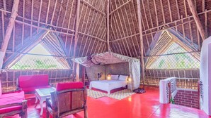 Una habitación con techo alto, una cama, un sofá rojo y una pequeña mesa.