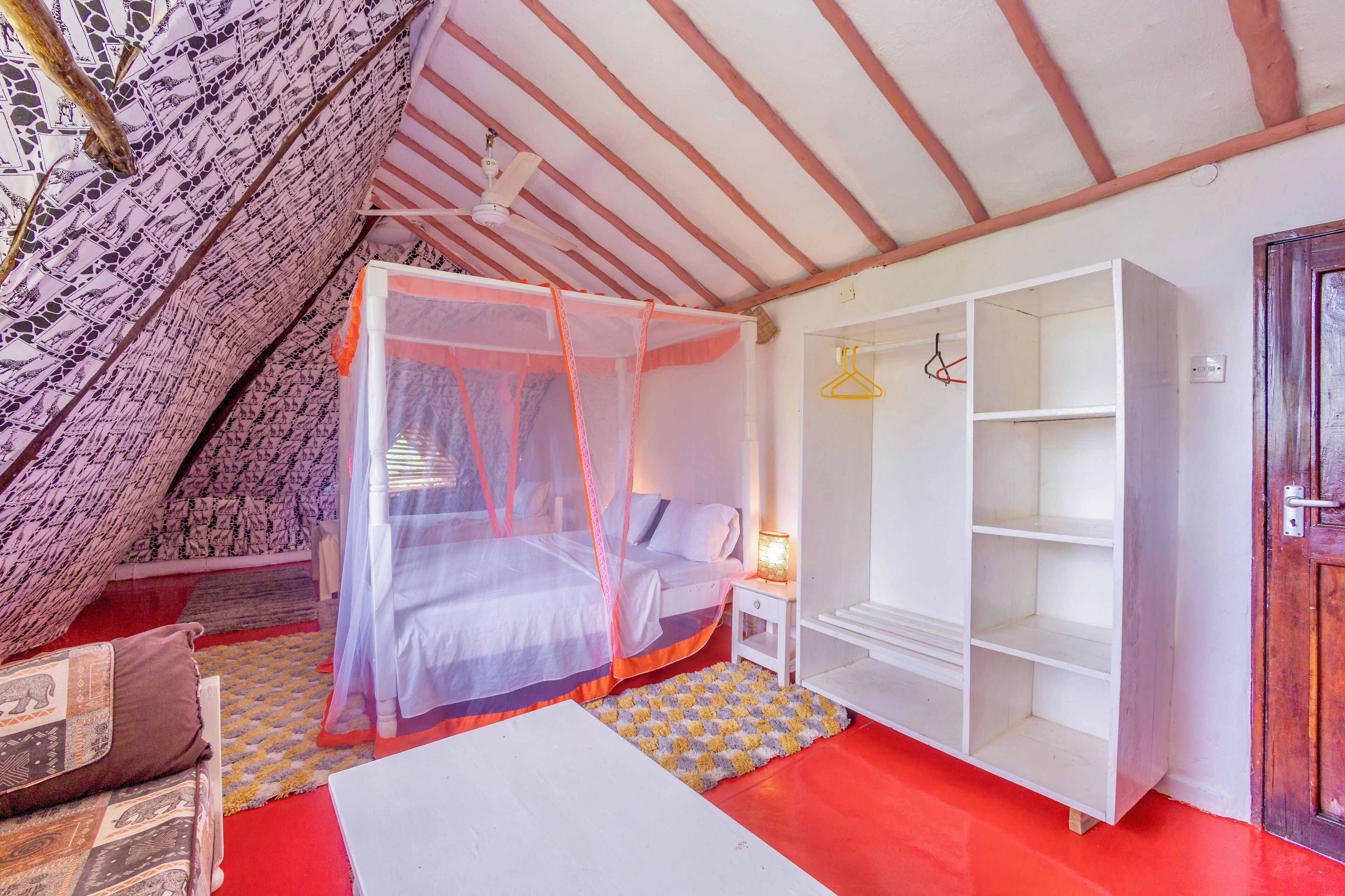 Ein Schlafzimmer mit einem Himmelsbett, einem weißen Kleiderschrank und einem roten Boden.