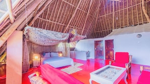 Una habitación con cama, sofá, una mesita y una silla roja.