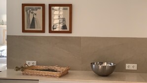 A kitchen counter with a woven basket and a metal bowl. There are two framed pictures on the wall above.